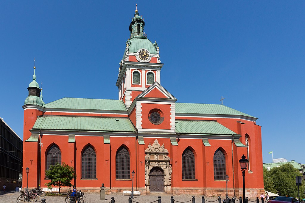 Saint James' Church is brightly colored with a red exterior and a green copper-clad roof.